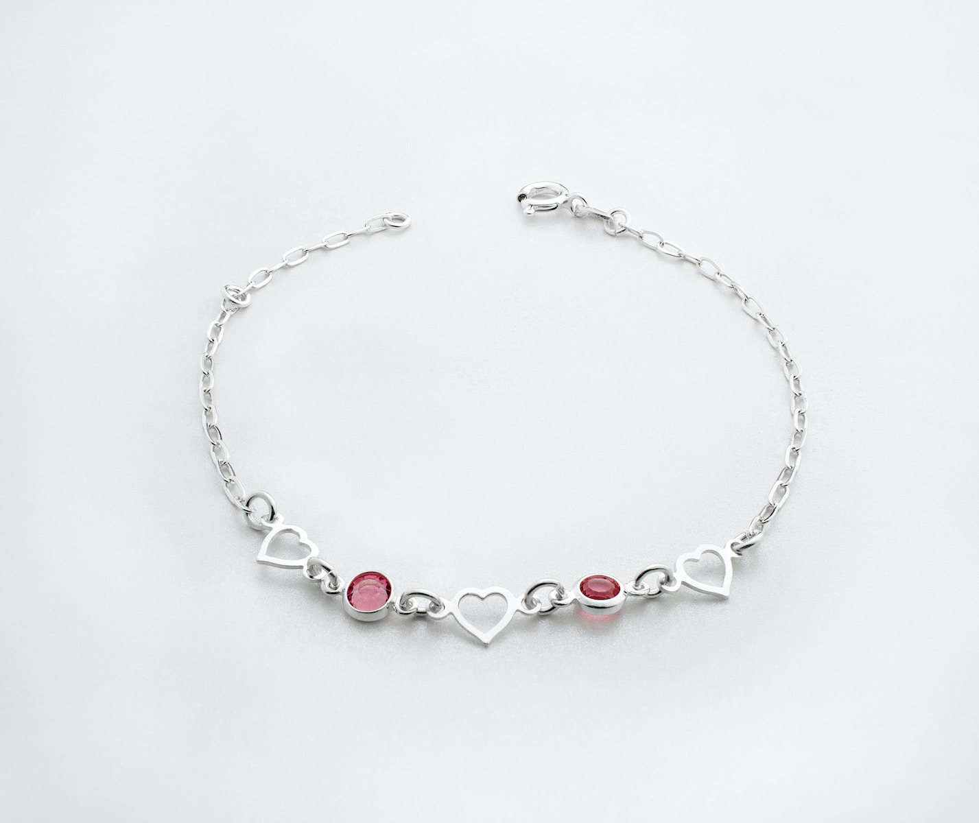 a silver bracelet with hearts and two red stones
